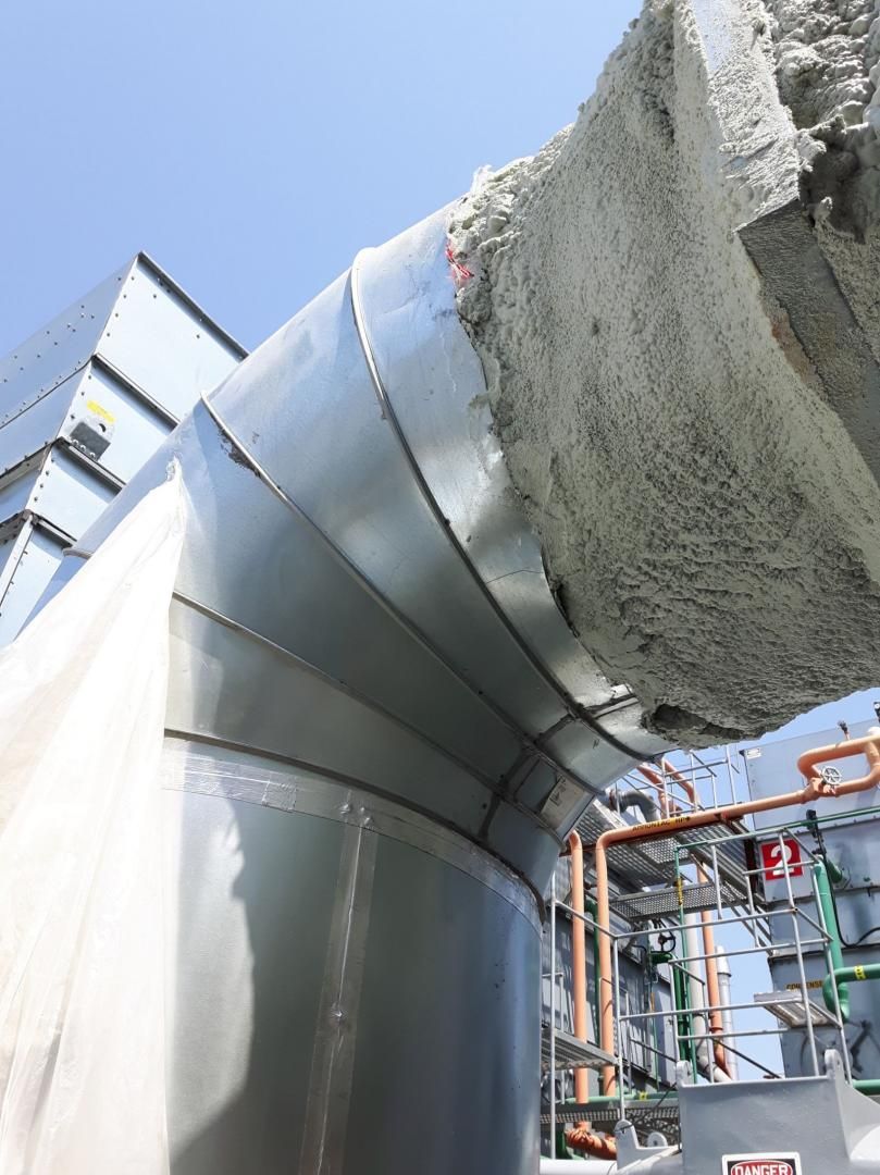 Grand tuyau industriel enveloppé de métal argenté, avec isolation appliquée à l'extérieur.