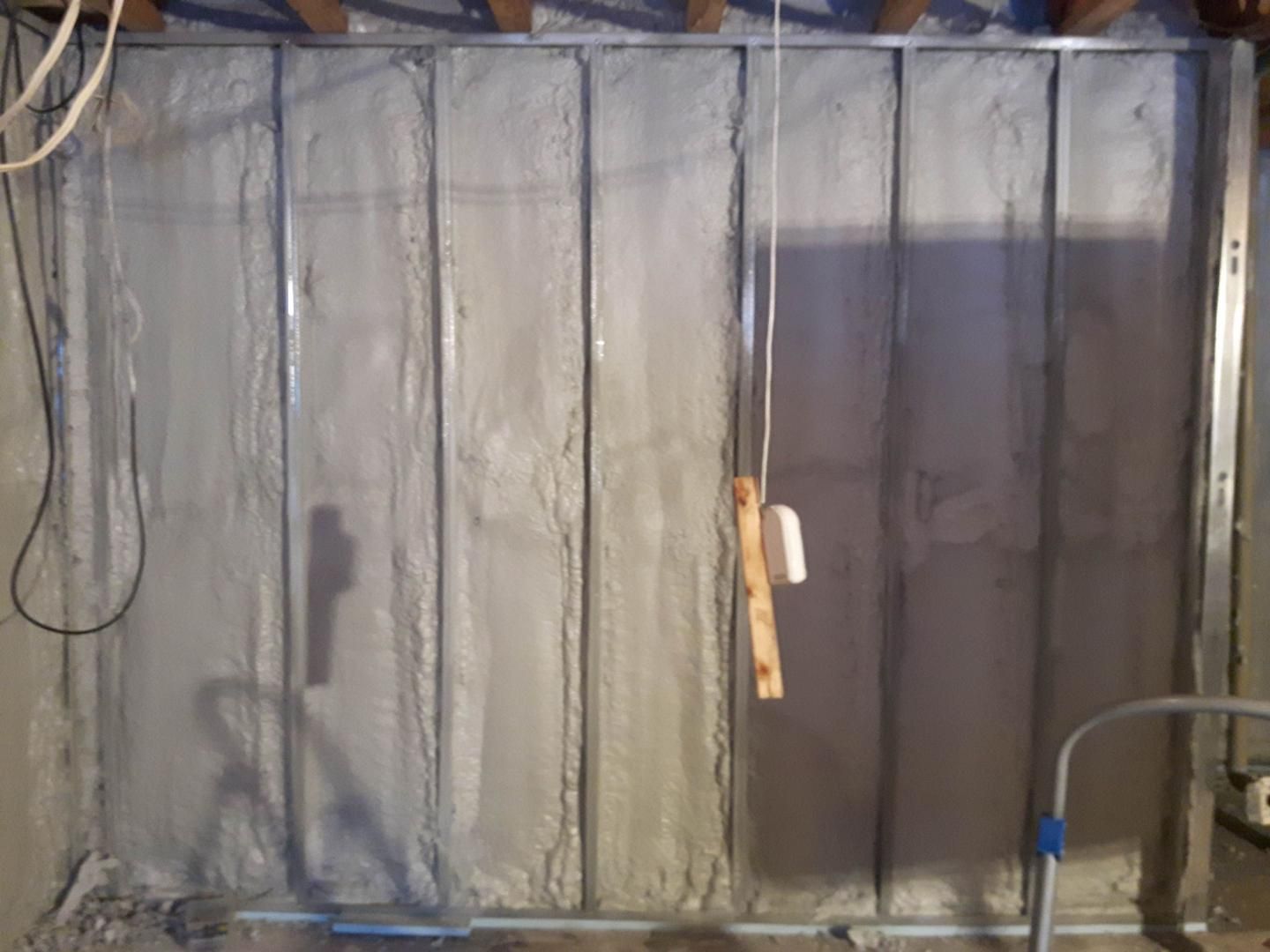 L’isolant gris remplit les montants métalliques d’un mur de sous-sol.