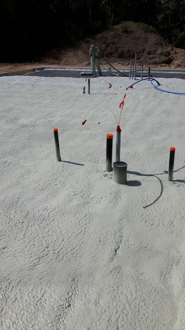 Fondations en béton avec tuyaux de plomberie saillants. Travaux de terrassement en cours.