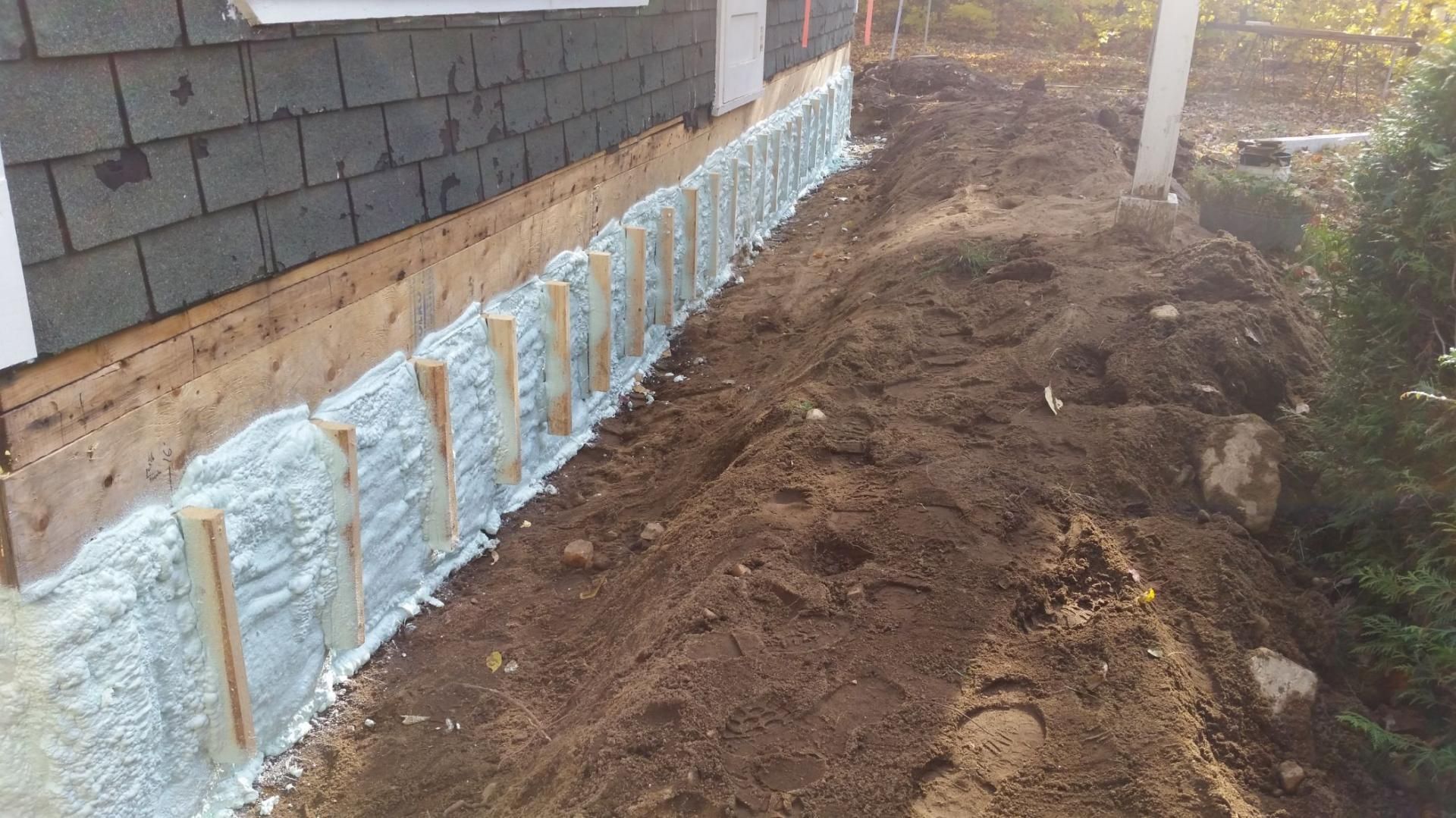 Fondation de maison en construction avec isolation en mousse et supports en bois.