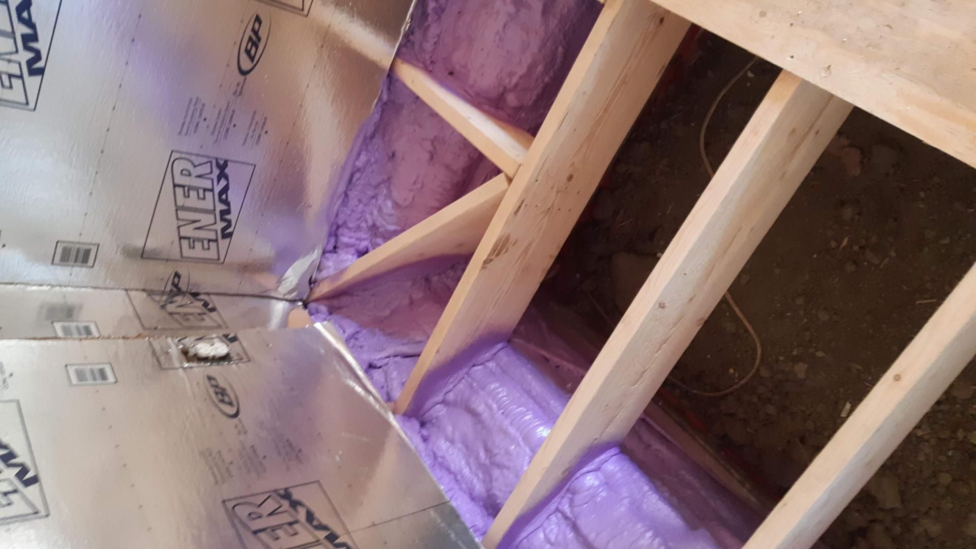 Poutres en bois avec isolation violette; tôles métalliques sur les murs.