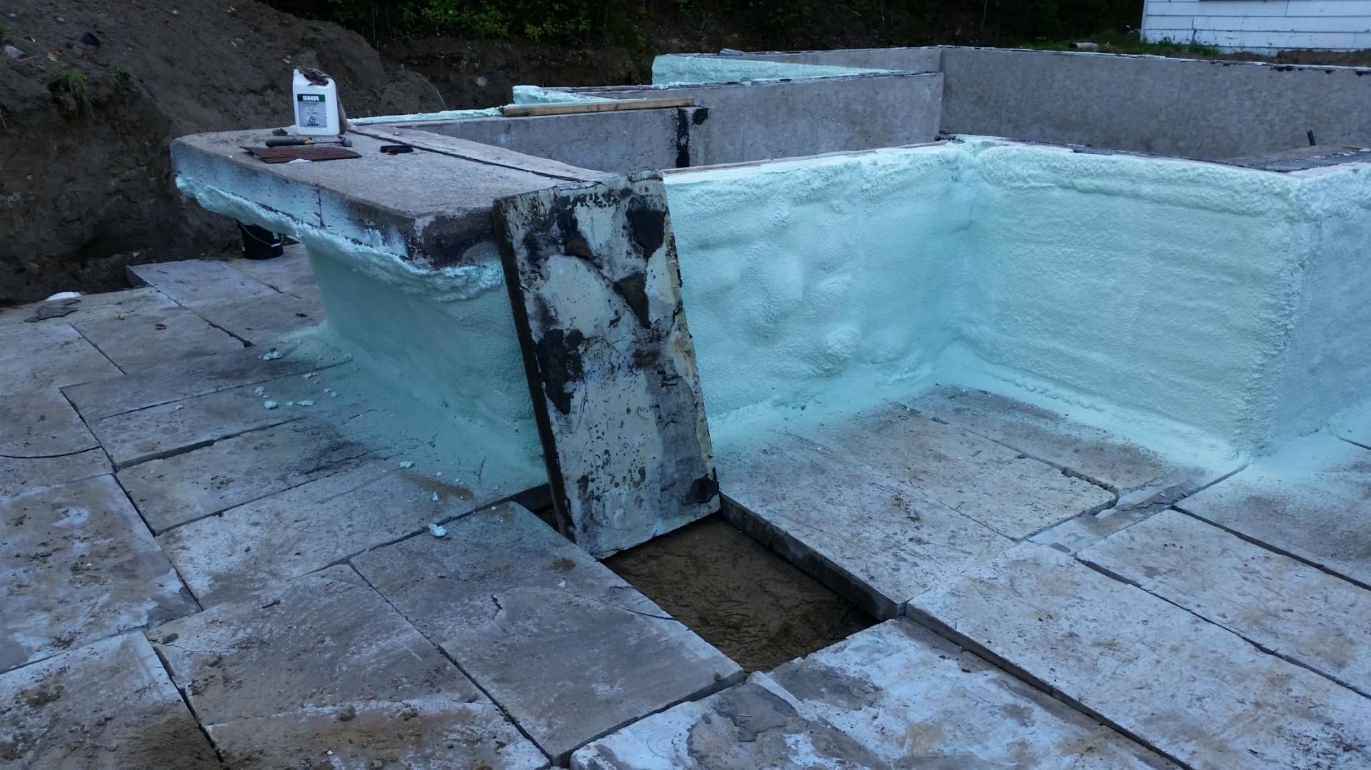 Structure en béton avec isolation en mousse verte appliquée, probablement pour une fondation.