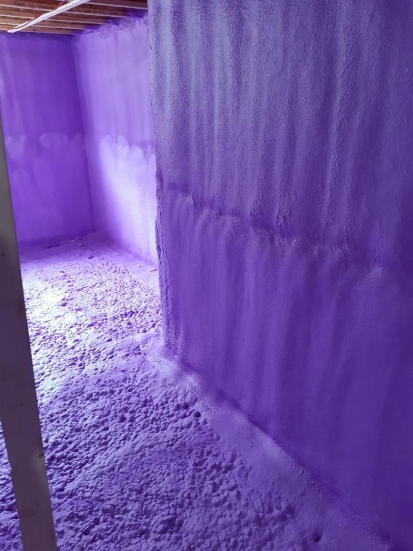 L'isolant en mousse pulvérisée violette recouvre les murs et le sol du sous-sol.