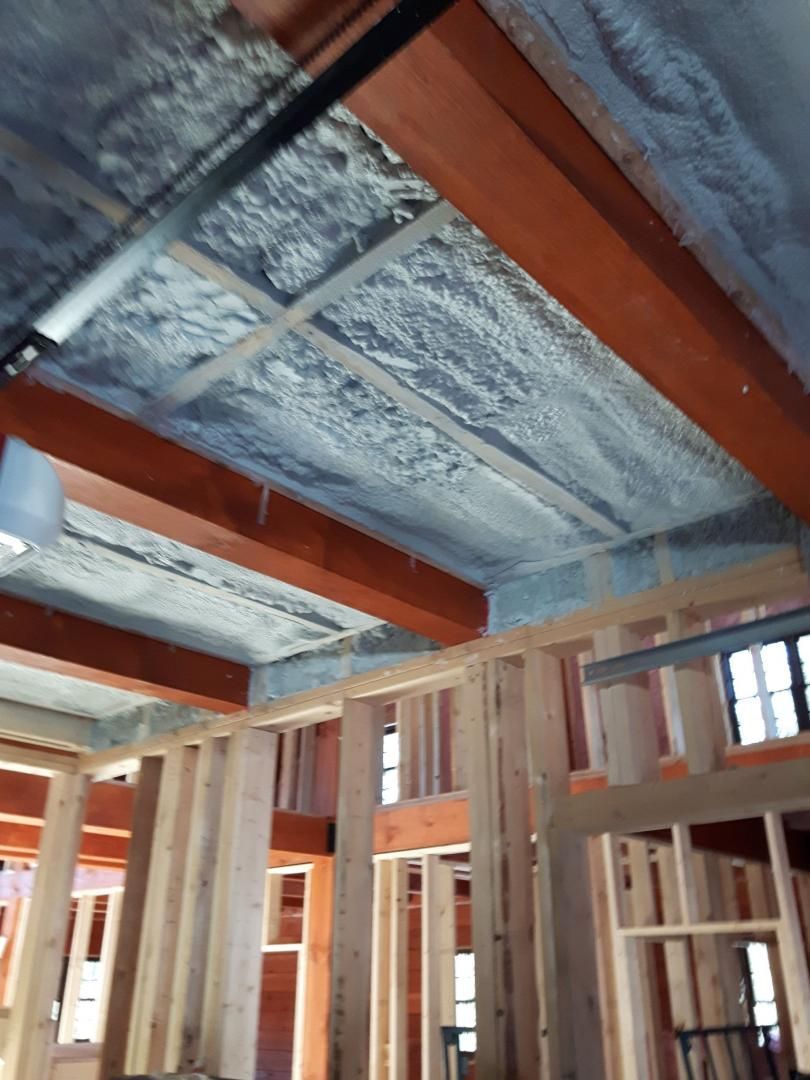 Poutres et charpente en bois soutenant un plafond recouvert d'isolant gris dans un intérieur de nouvelle construction.