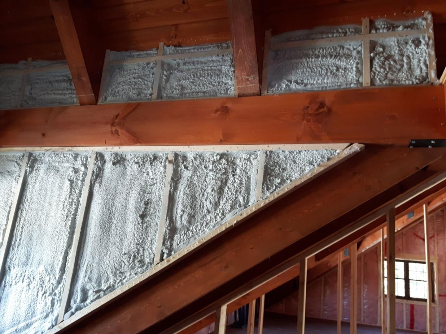 Isolation en mousse pulvérisée entre les poutres en bois dans un grenier.