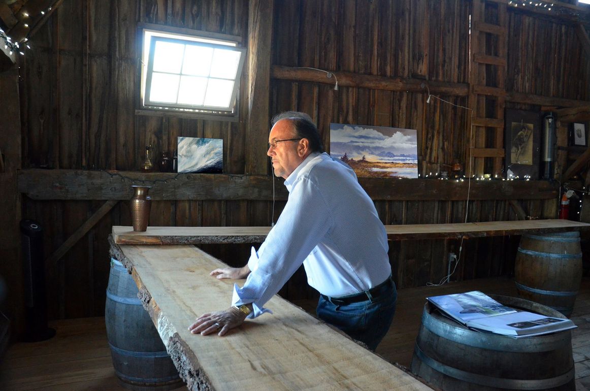 J. Douglas Thompson in rustic barn with some of his paintings in the background