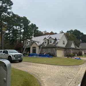 A white truck is parked in front of a house that is being painted.