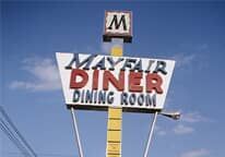 A mayfair diner dining room sign is against a blue sky.