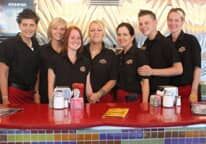 A group of people are posing for a picture at a diner.