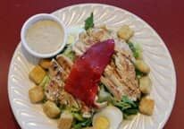 A white plate topped with a salad and a small bowl of dressing.