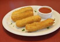 A white plate topped with fried mozzarella sticks and a dipping sauce.