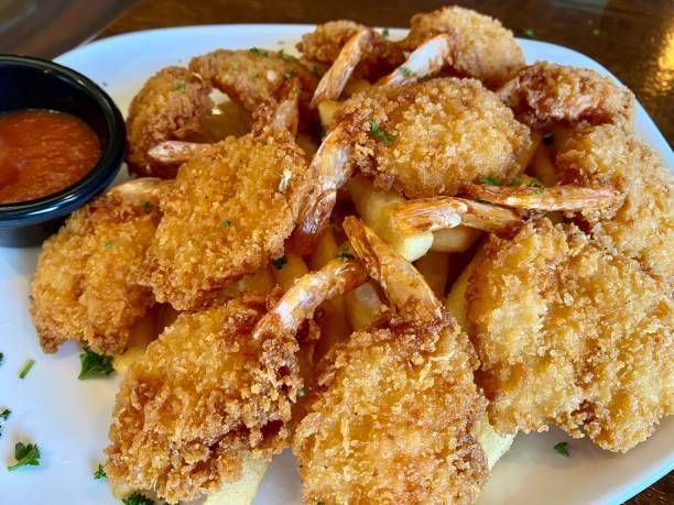 A plate of fried shrimp and french fries with dipping sauce.