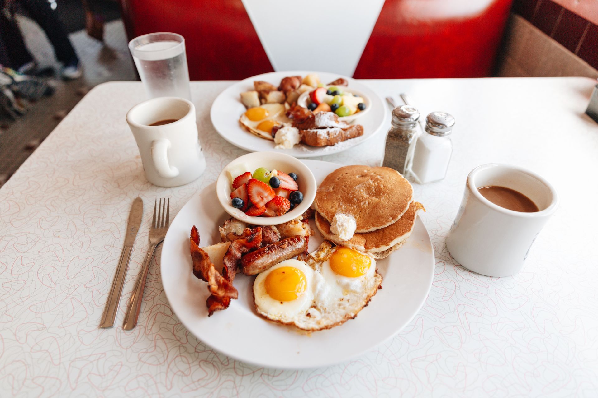 A table topped with plates of food , coffee , and utensils.