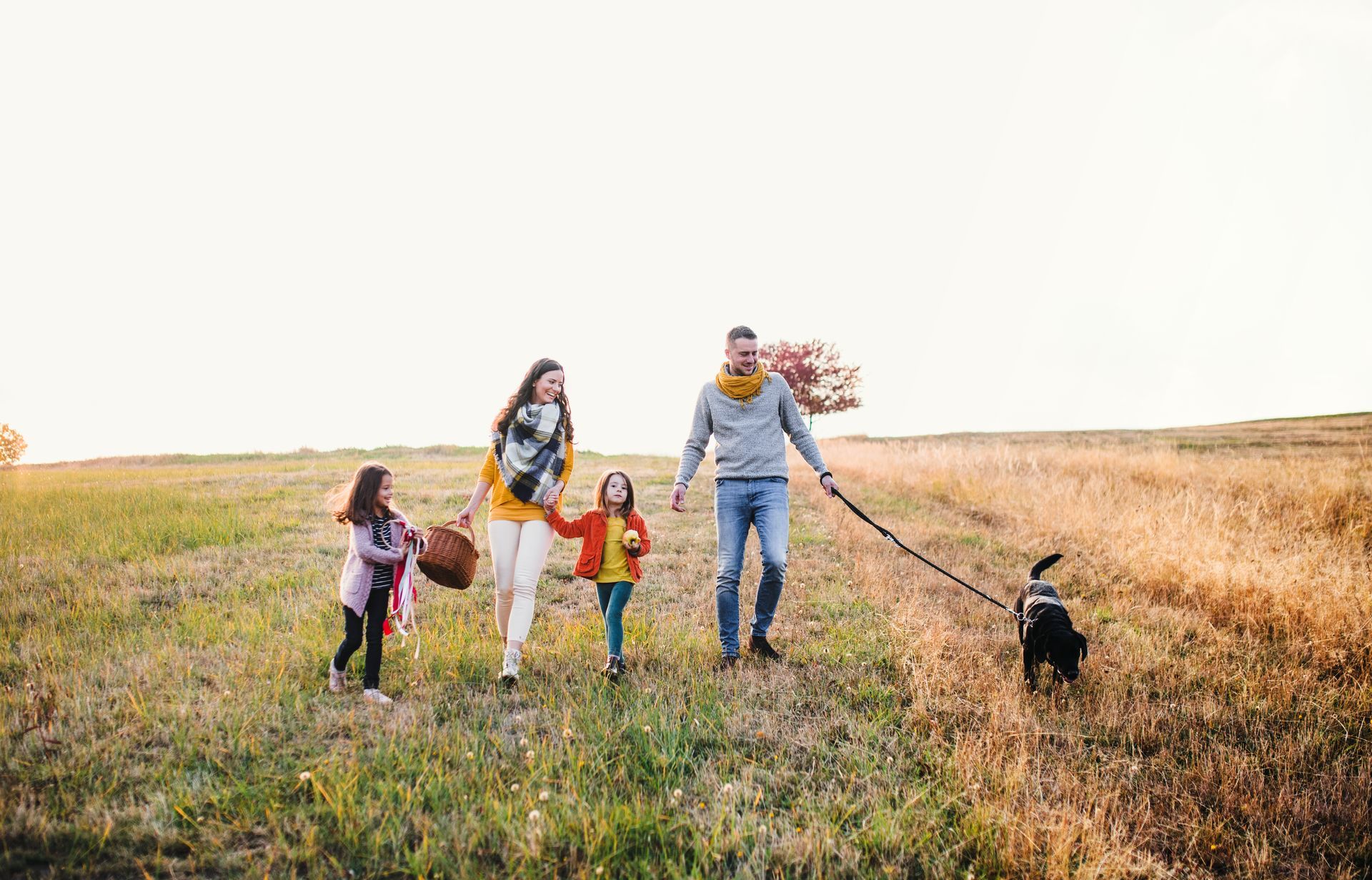 A family is walking a dog in a field.
