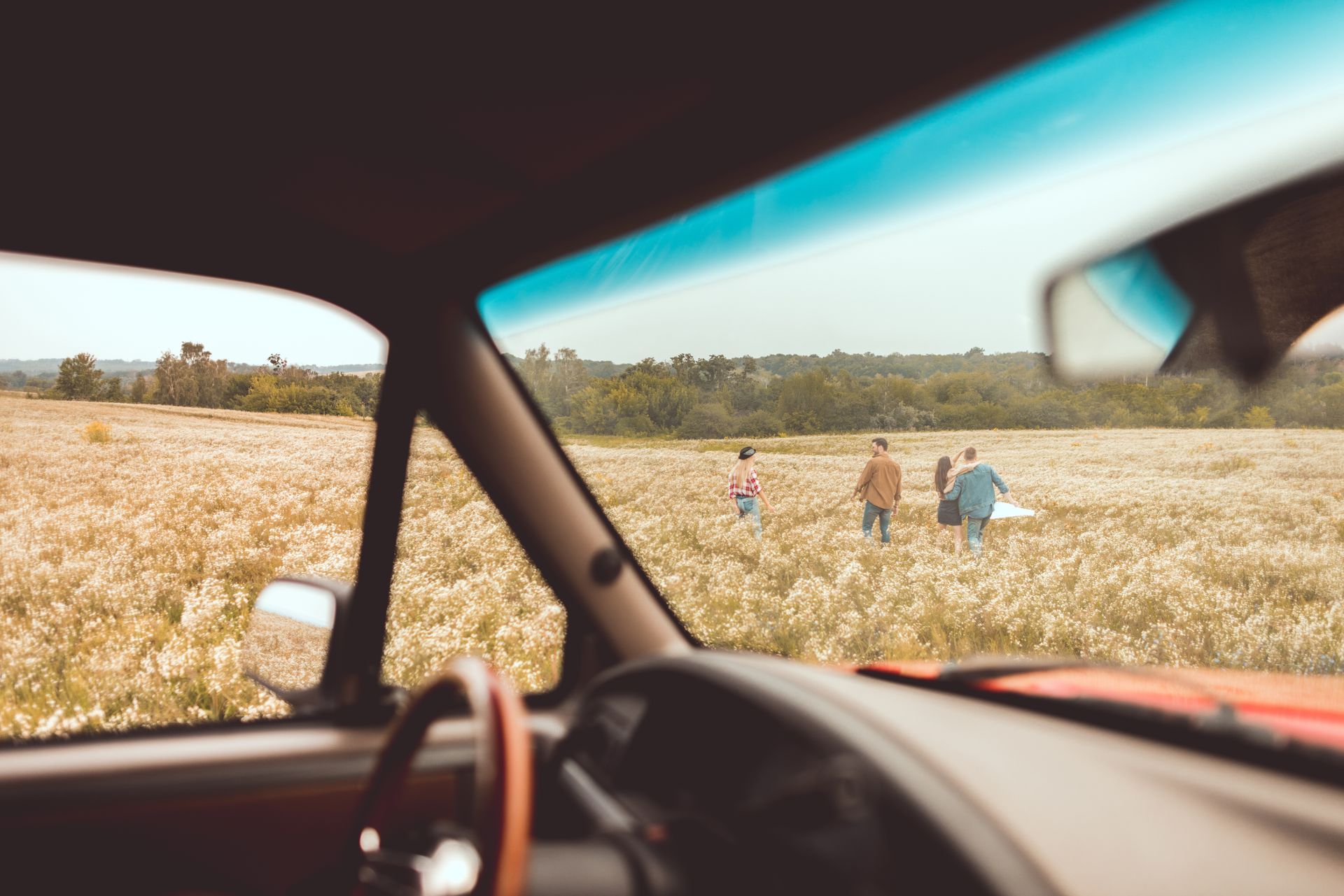 A family is walking through a field in a car.
