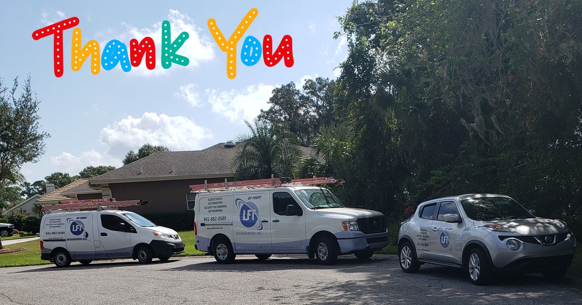 Three service vehicles parked on a driveway with a residential house and trees in the background, a 
