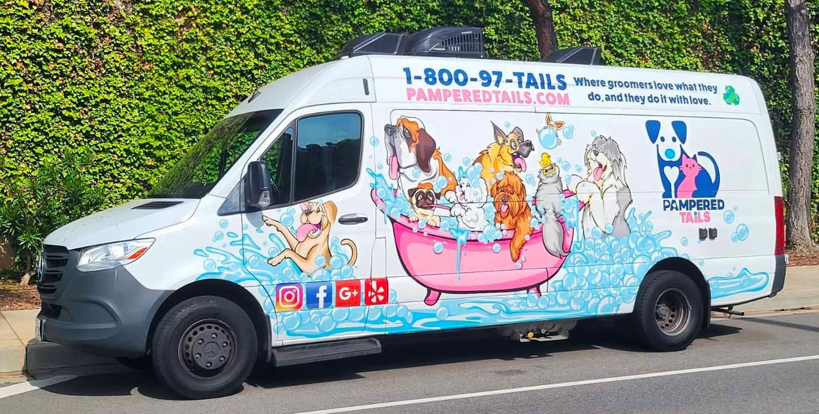 Mobile dog grooming van with cartoon dogs in a bathtub. White vehicle with blue and pink graphics.