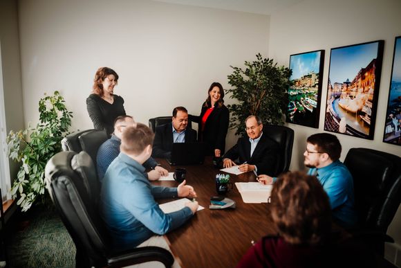 A group of people are sitting around a table shaking hands.