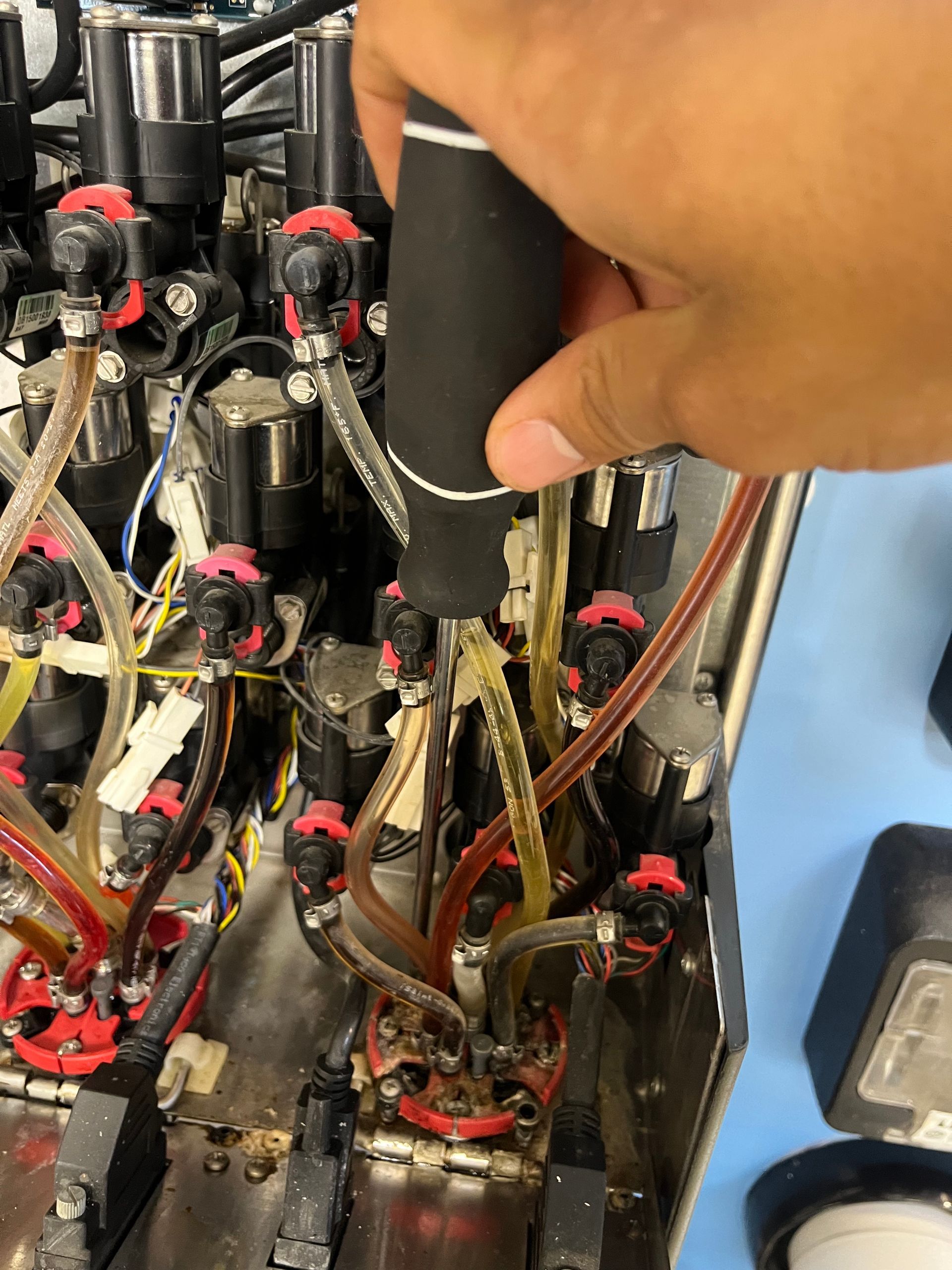 A technician working on a soda machine with a screwdriver.