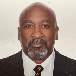 A bald man with a beard wearing a suit and tie