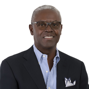 A man wearing glasses and a suit is smiling for the camera