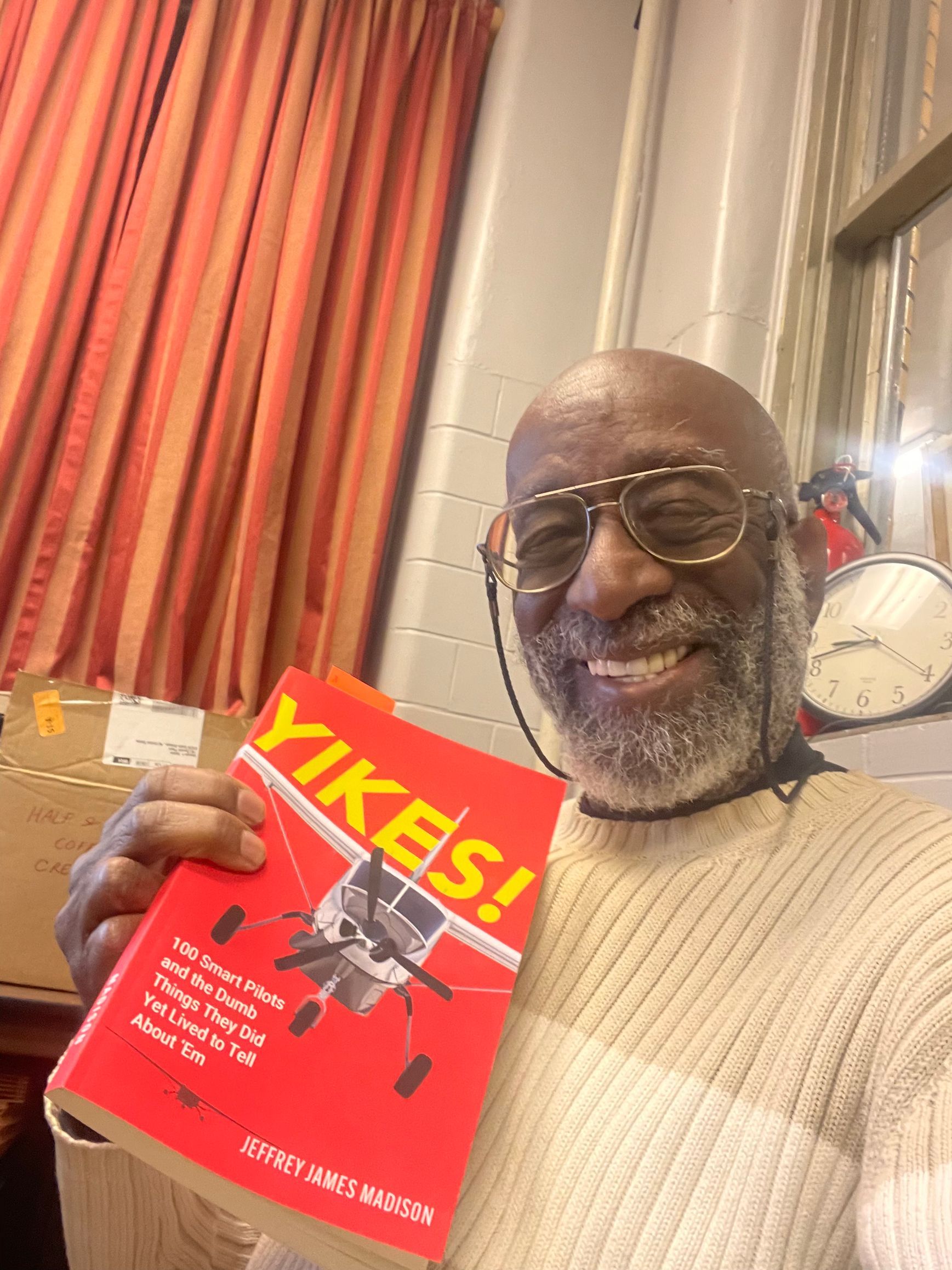 A man is holding a red book titled yikes !