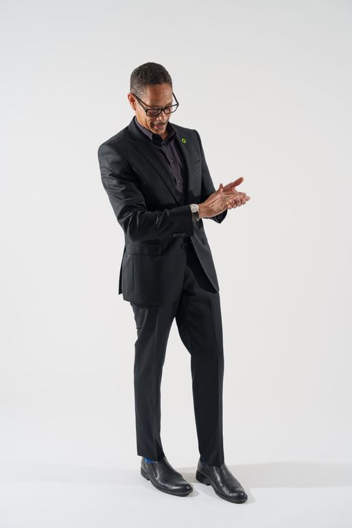 A man in a suit and tie is standing in front of a white background.