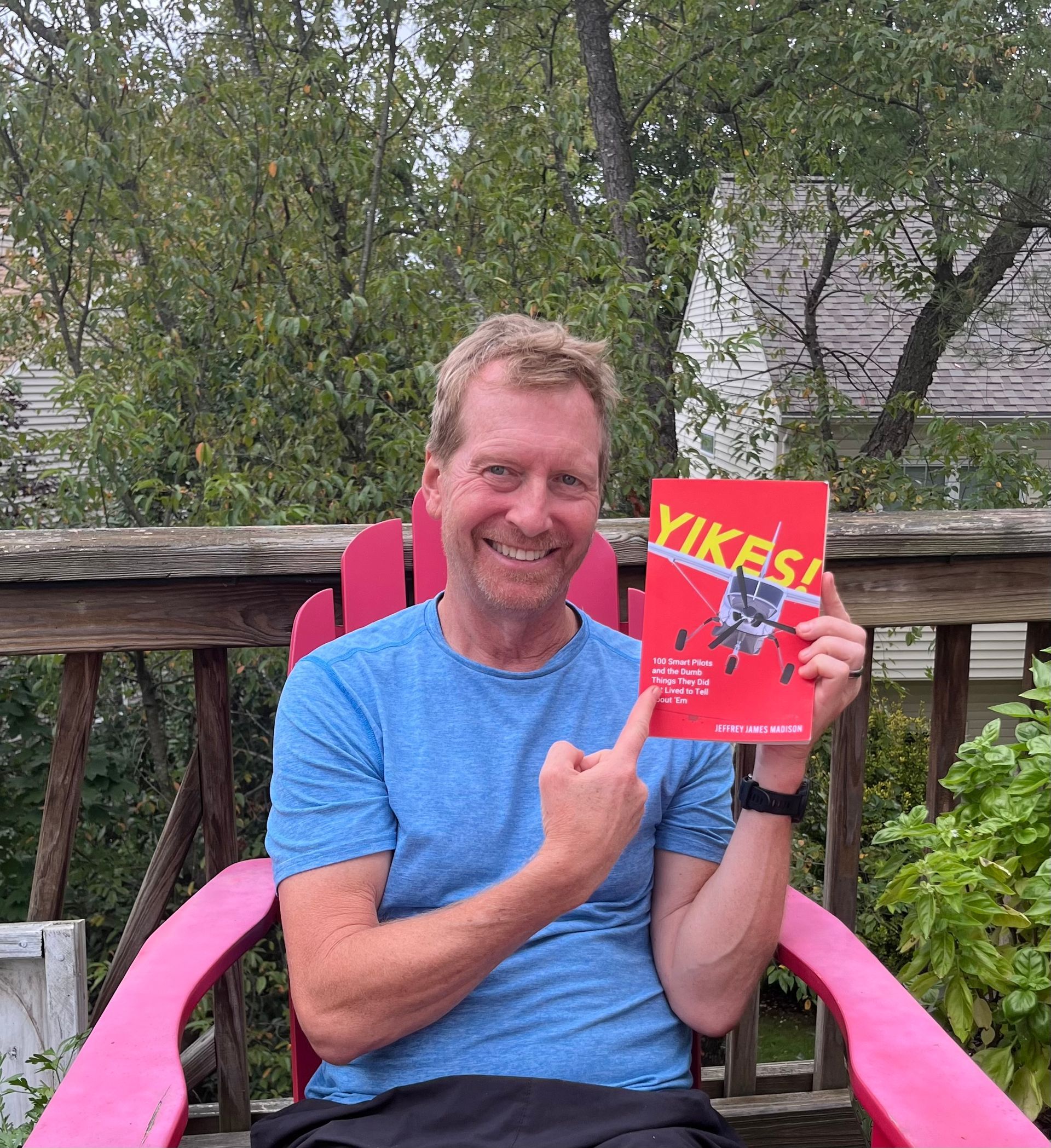 A man is sitting in a pink chair holding a book.