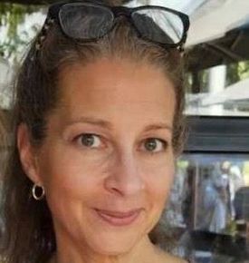 A woman wearing a red sweater is smiling for the camera