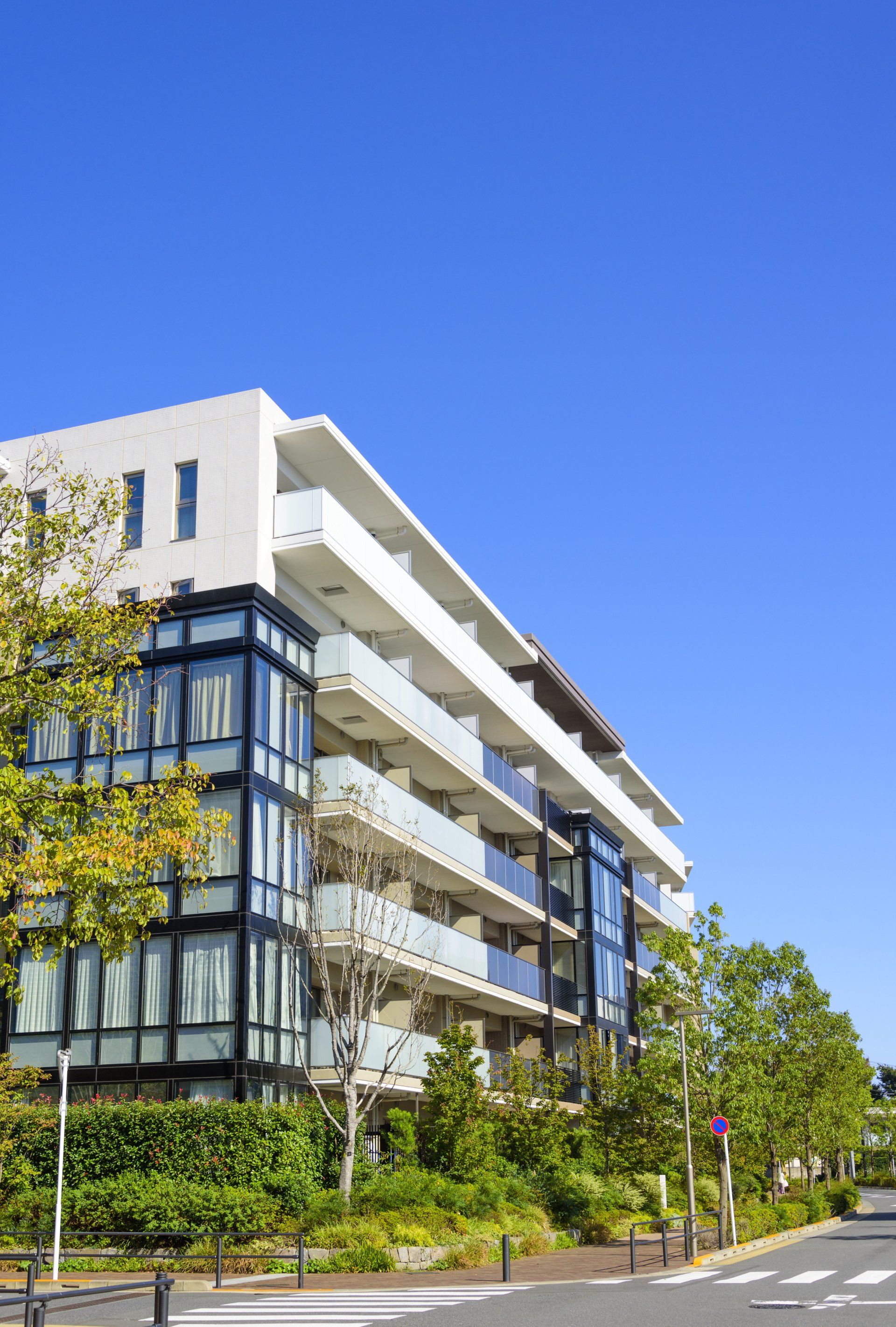 Un grand immeuble d'appartements avec beaucoup de fenêtres se trouve à côté d'une rue.