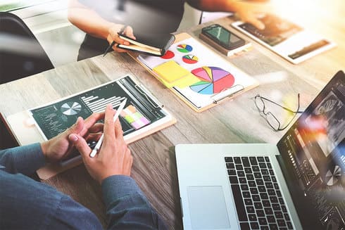 Un groupe de personnes sont assises à une table avec un ordinateur portable et une tablette.
