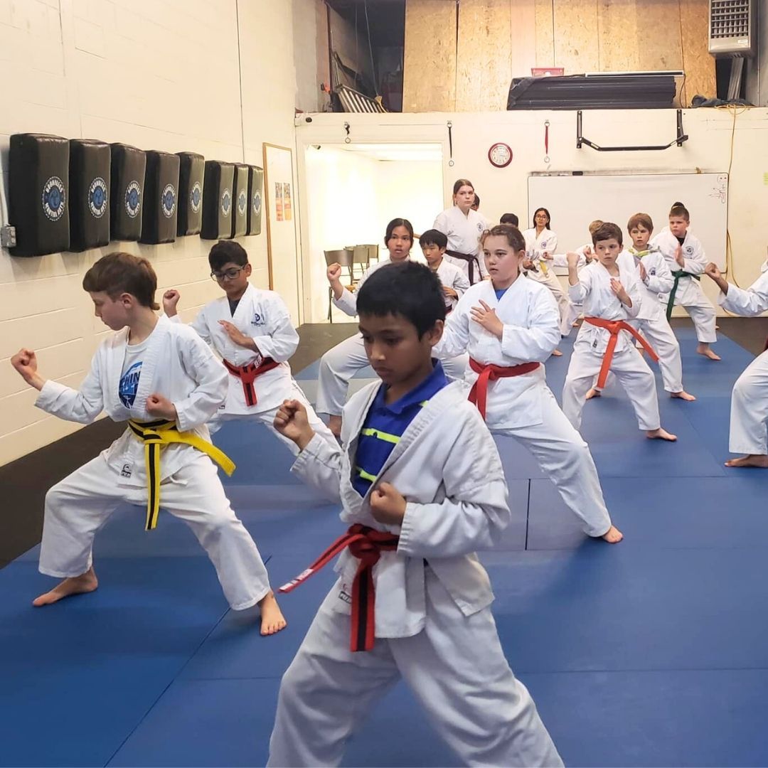 Two children grappling on a mat, one in a headlock.