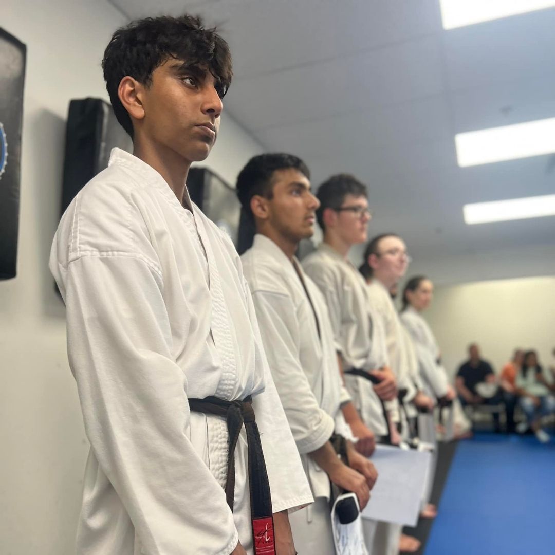 Two men grappling on a mat, one in blue, the other in black.