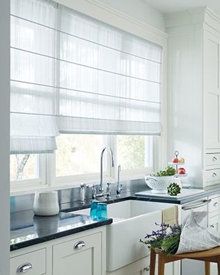 Kitchen with white cabinets, sink, and windows with light-colored Roman shades.