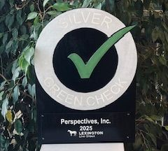 White pillar with a sign that has a green checkmark on it; Perspective, Inc.
