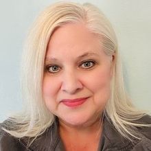 A close up of a woman 's face with blonde hair and a gray jacket.