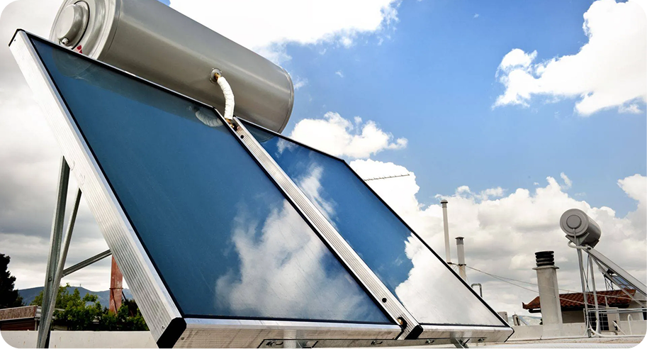 Solar water heaters with blue reflective panels and white tanks on a rooftop under a cloudy sky