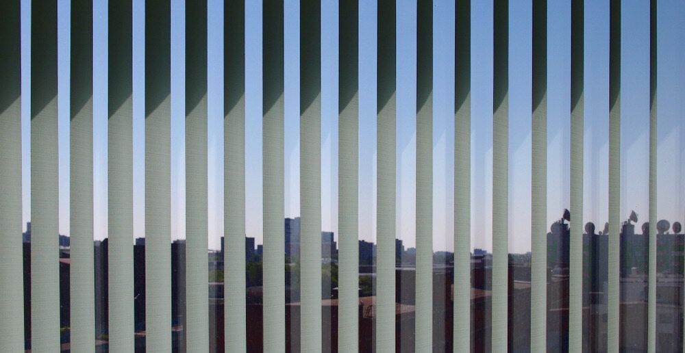 A View Of A City Skyline Through Vertical Blinds — Summerland Screens & Awnings In Ballina, NSW