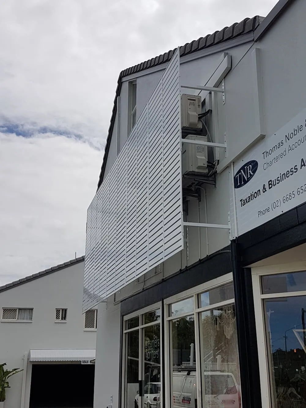 A White Building With A White Lattice On The Side Of It — Summerland Screens & Awnings In Evans Head, NSW