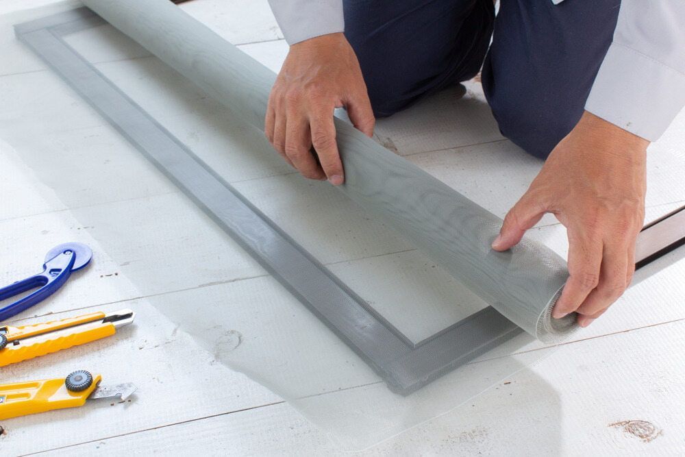 A Person Is Installing A Screen Door On A Window — Summerland Screens & Awnings In Suffolk Park, NSW