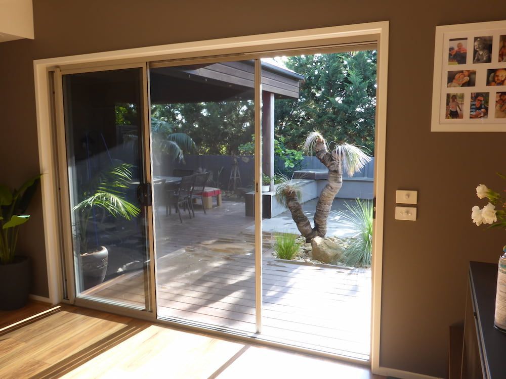 A Living Room With A Sliding Glass Door Leading To A Deck — Summerland Screens & Awnings In Ballina, NSW
