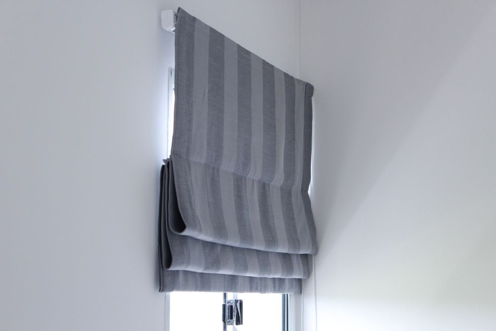A Gray Striped Roman Shade Is Hanging On A Window — Summerland Screens & Awnings In Alstonville, NSW
