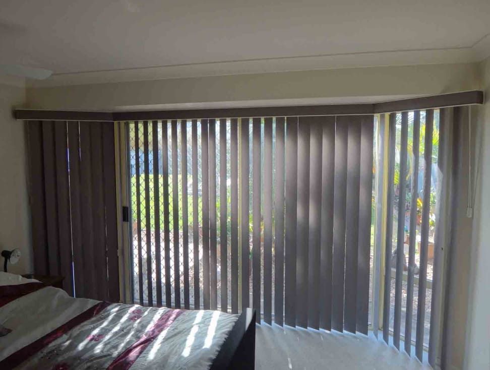 A Bedroom With A Bed And Sliding Glass Doors With Vertical Blinds — Summerland Screens & Awnings In Evans Head, NSW