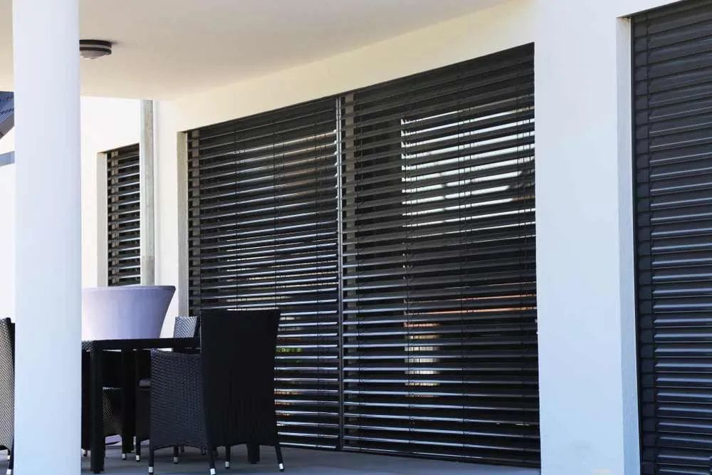 A Patio With A Table And Chairs And Black Blinds — Summerland Screens & Awnings In Ballina, NSW