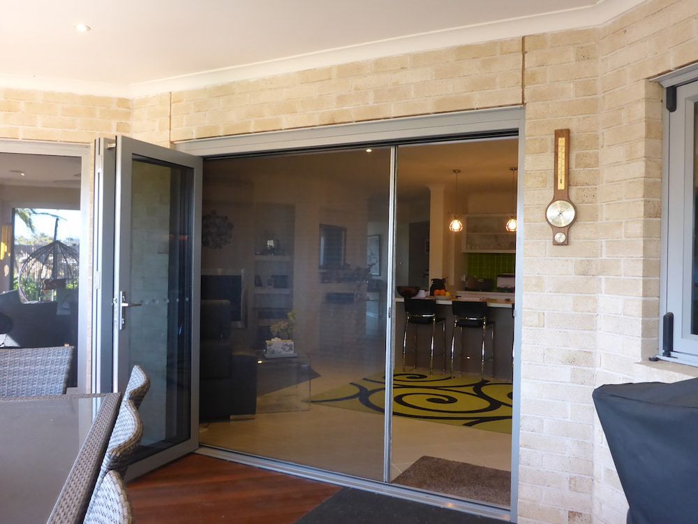 A Sliding Glass Door Is Open To A Living Room — Summerland Screens & Awnings In Ballina, NSW