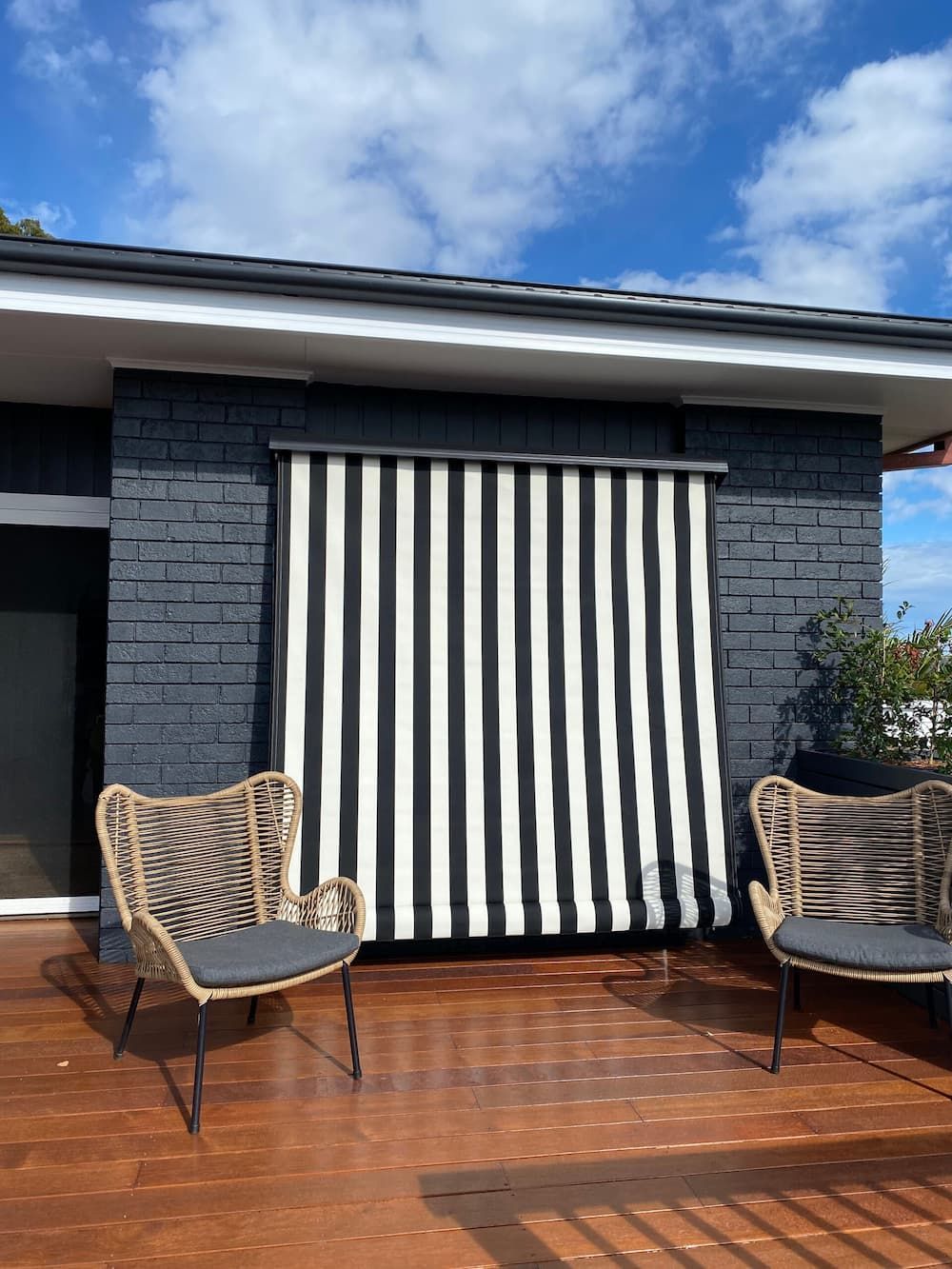 A Black And White Striped Awning Is Hanging On The Side Of A House — Summerland Screens & Awnings In Lennox Head, NSW