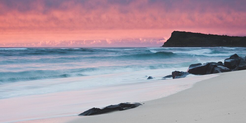 A Beach With A Mountain In The Background At Sunset — Summerland Screens & Awnings In Lennox Head, NSW