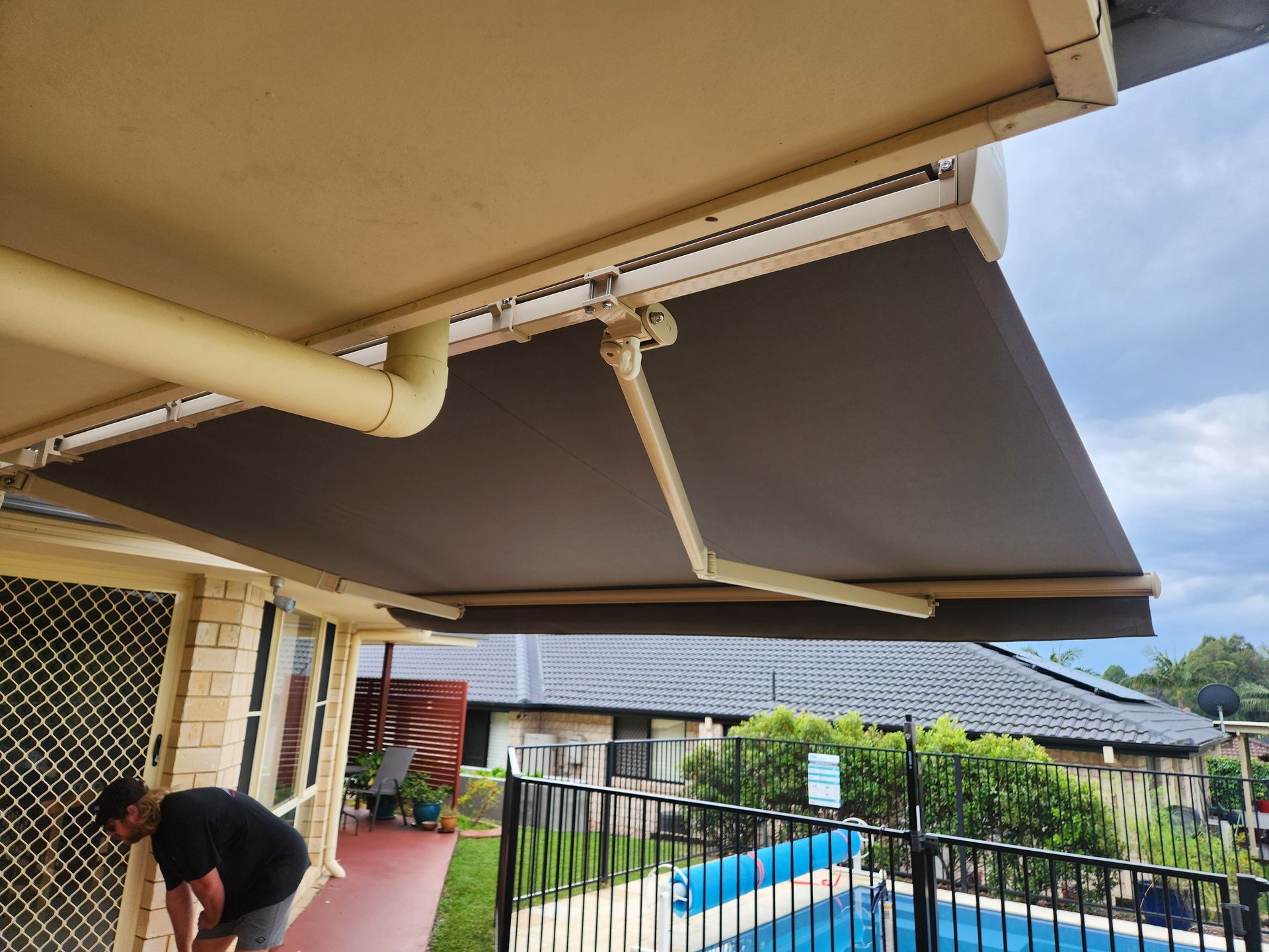 A cream folding arm awning oer a pool— Summerland Screens & Awnings In Ballina, NSW