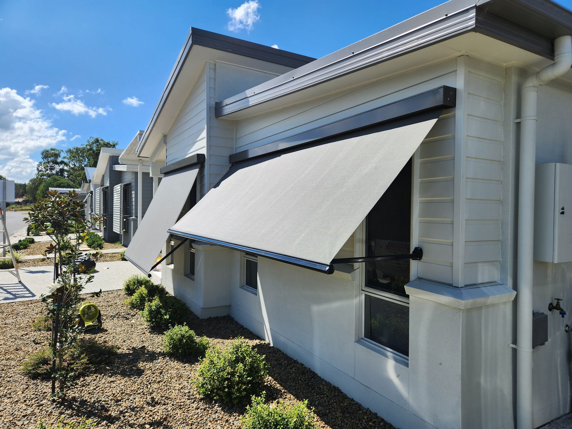 Pivot Arm Awnings on the side of a white house — Summerland Screens & Awnings In Ballina, NSW