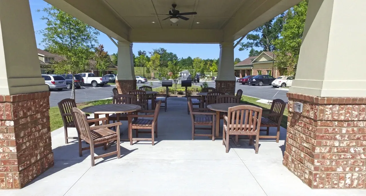 Covered outdoor pavilion with wooden tables and chairs in a residential complex.